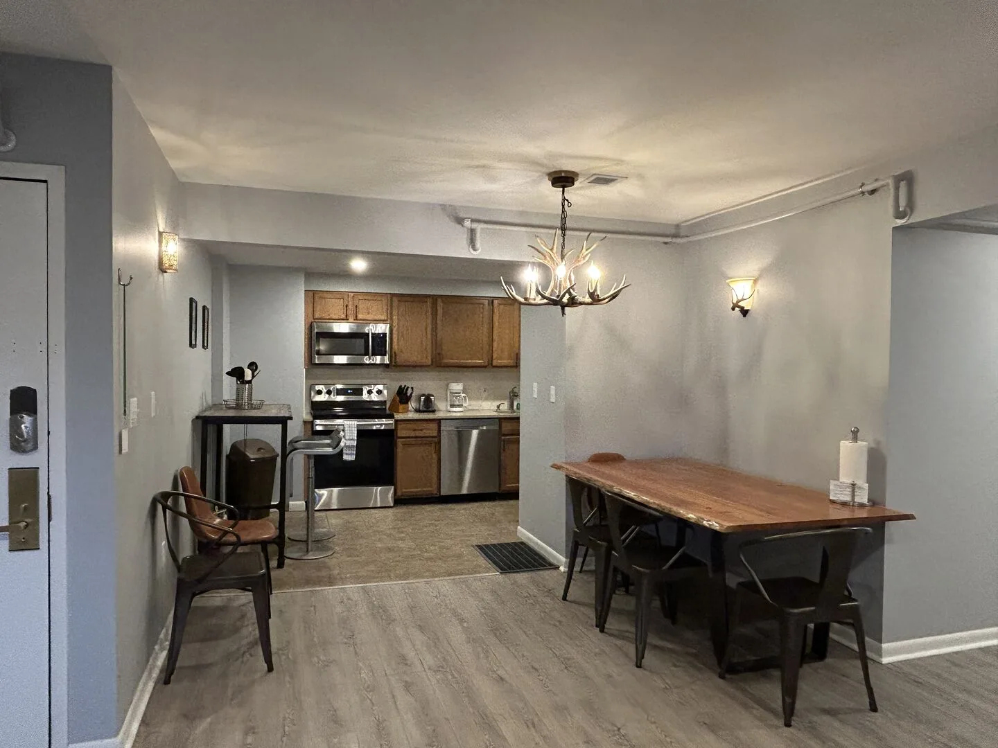 An open-plan kitchen and dining area with a wooden table and dark seating.