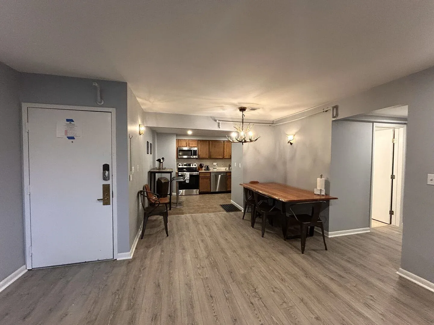 Un comedor abierto con cocina, una mesa de madera y una lámpara colgante.