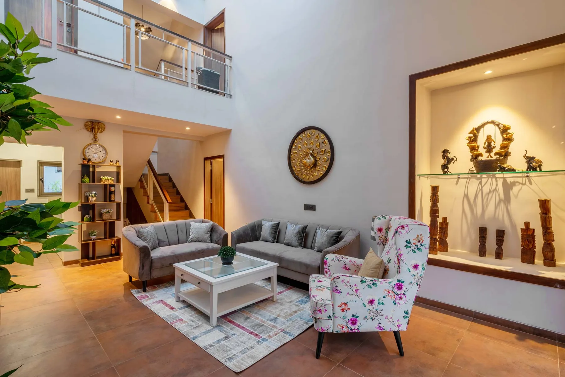 Una sala de estar con asientos grises y un sillón floral.