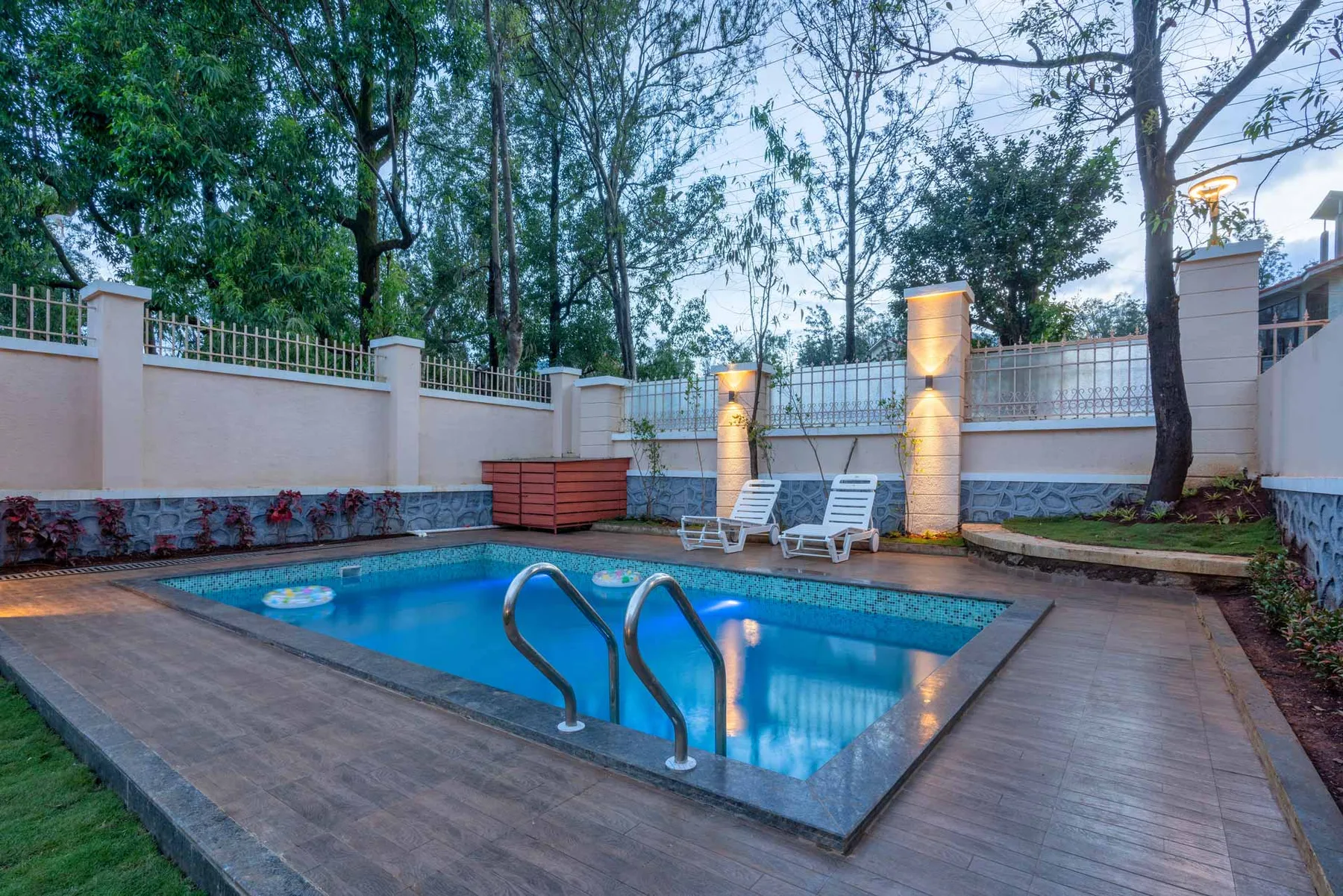 Una piscina al aire libre está rodeada por una terraza de madera y asientos.