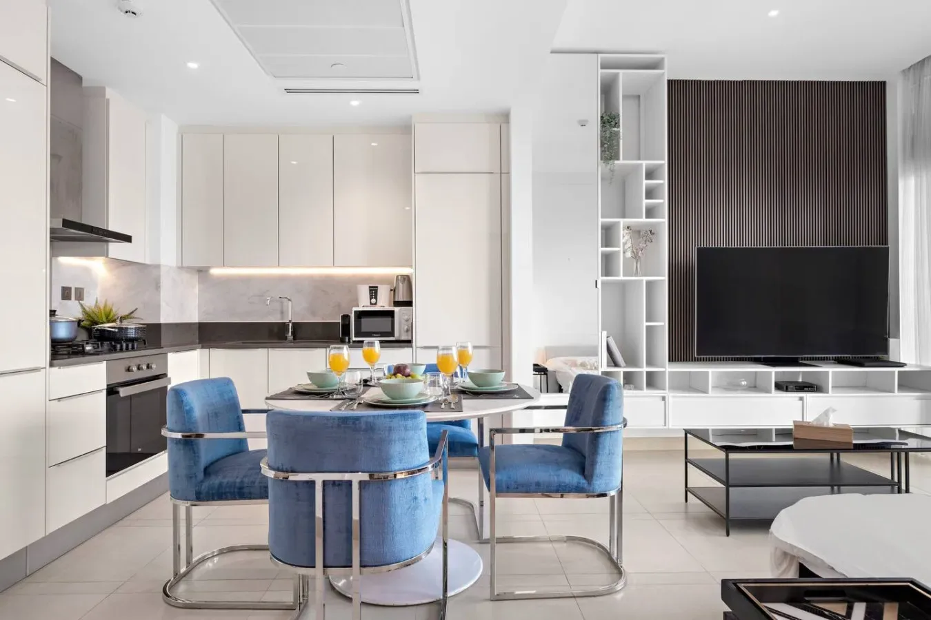 A bright open-plan kitchen and dining area with blue seating around the table.