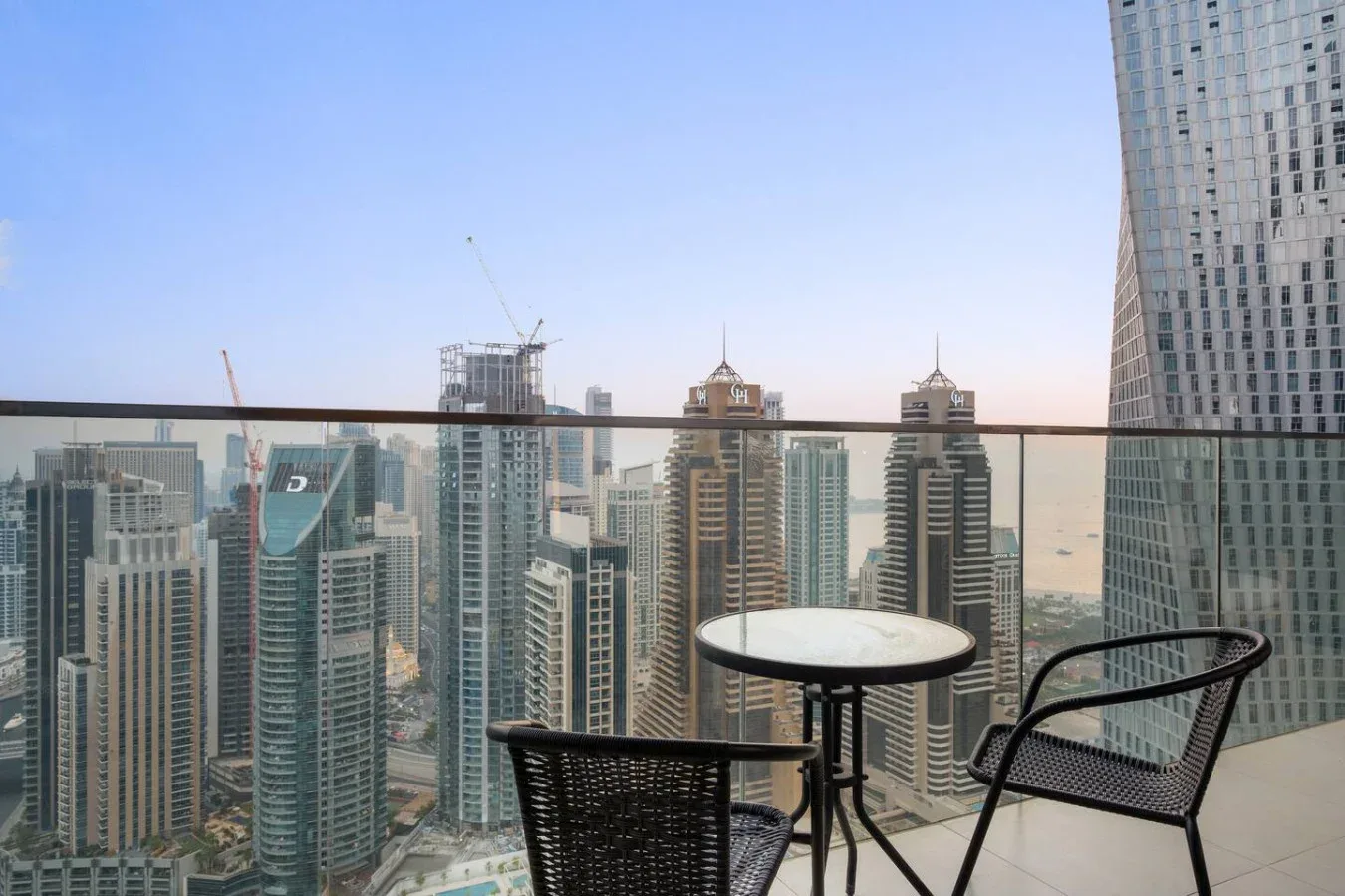 A balcony seating area overlooks a cluster of high-rise buildings.