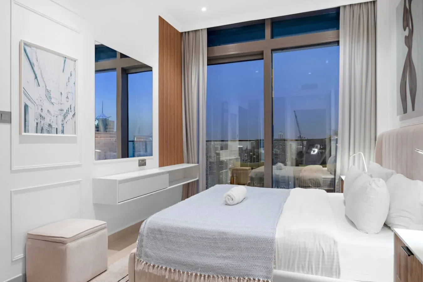 A bright bedroom with a neatly made bed beside large windows.