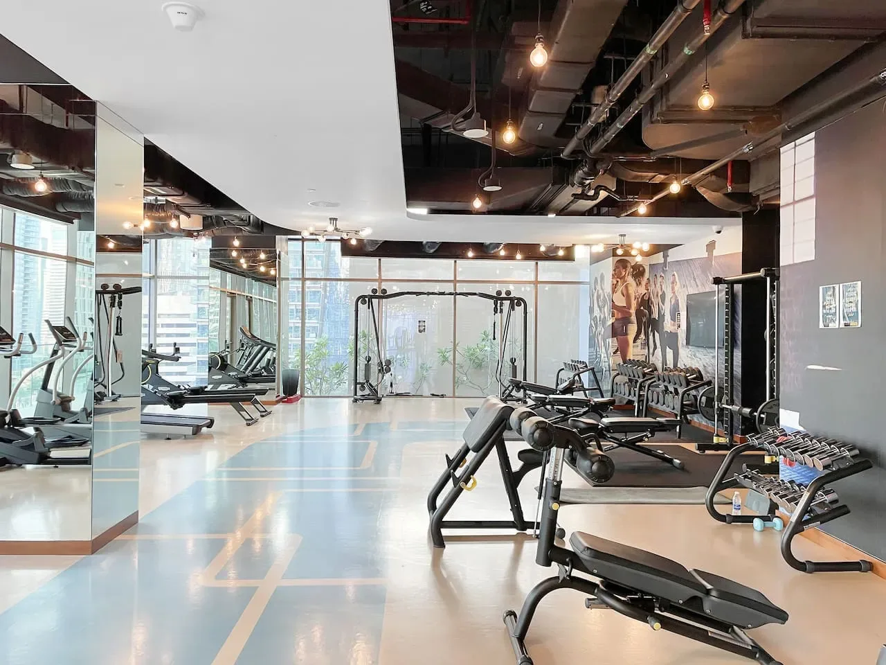 A gym with exercise machines, weight benches, and mirrored walls.
