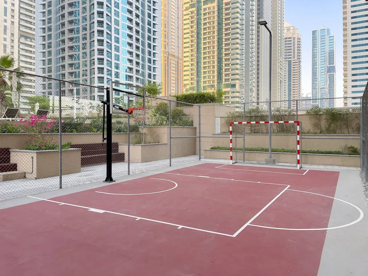 An outdoor court with painted lines and a small goal, surrounded by tall buildings.