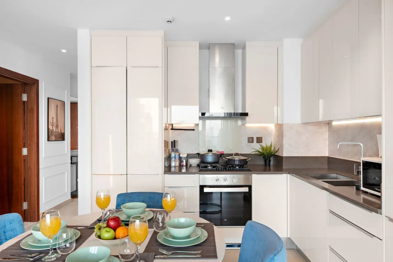 A bright modern kitchen with white cabinets, a central island, and dining seating.
