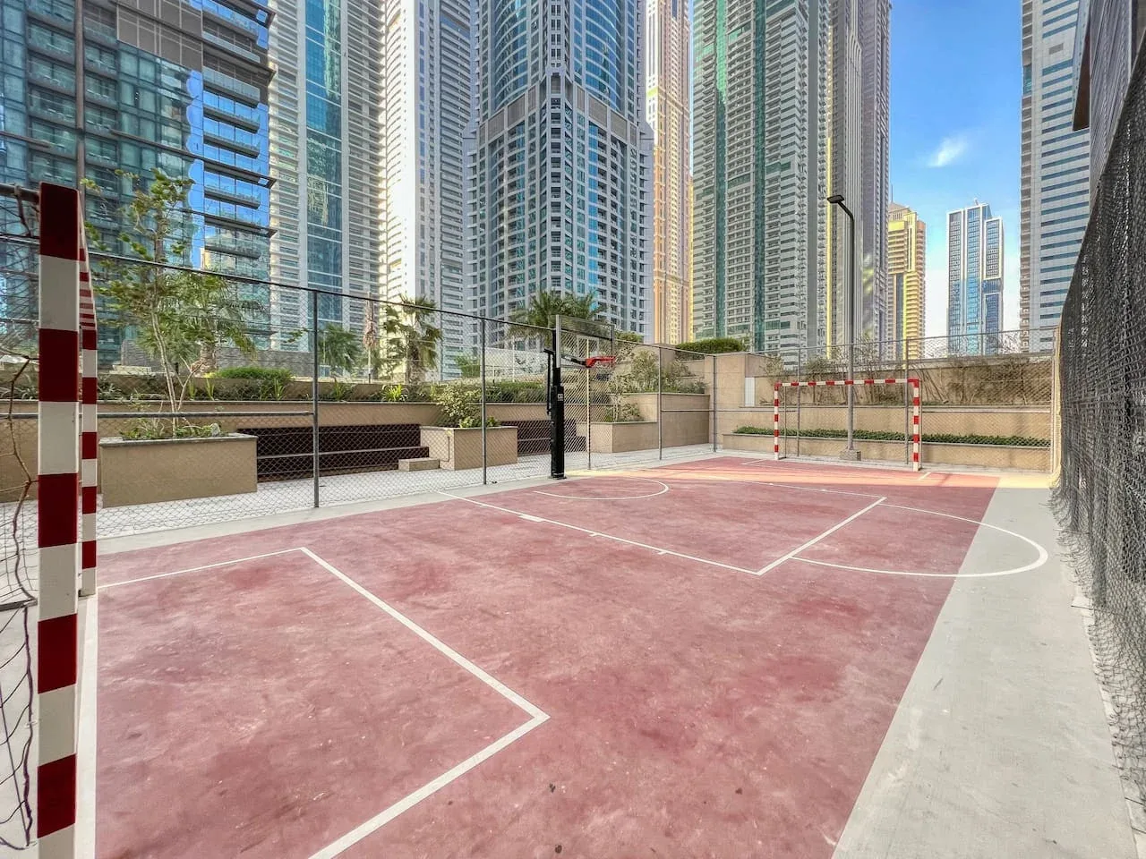 An outdoor sports court with red playing surface and white boundary lines.
