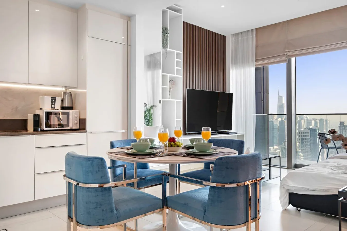 A bright dining and living area features a set table, seating, and large windows.