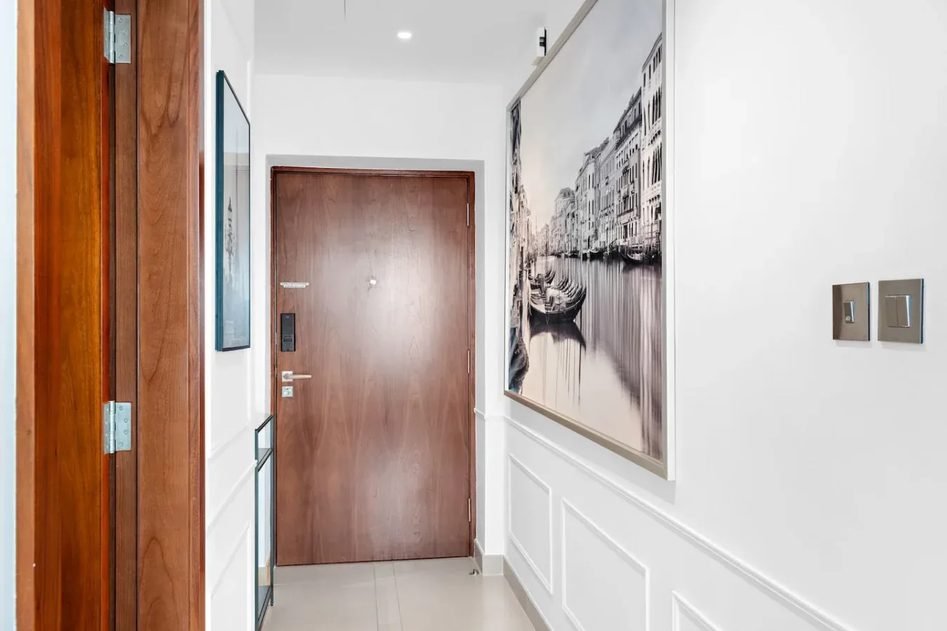 A bright hallway with a wooden entry door and framed wall art.