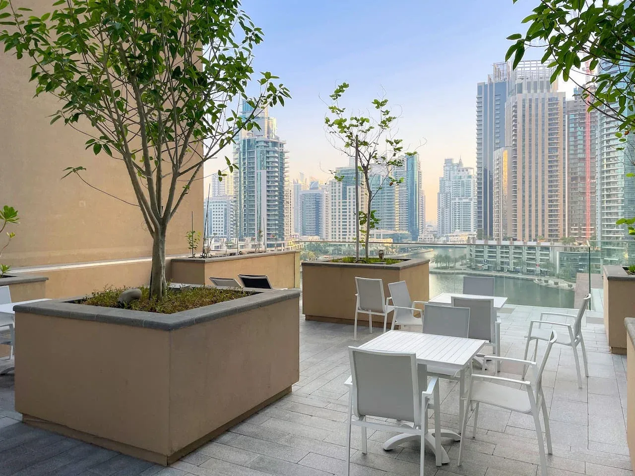 A rooftop terrace with outdoor seating and a view of nearby high-rise buildings.