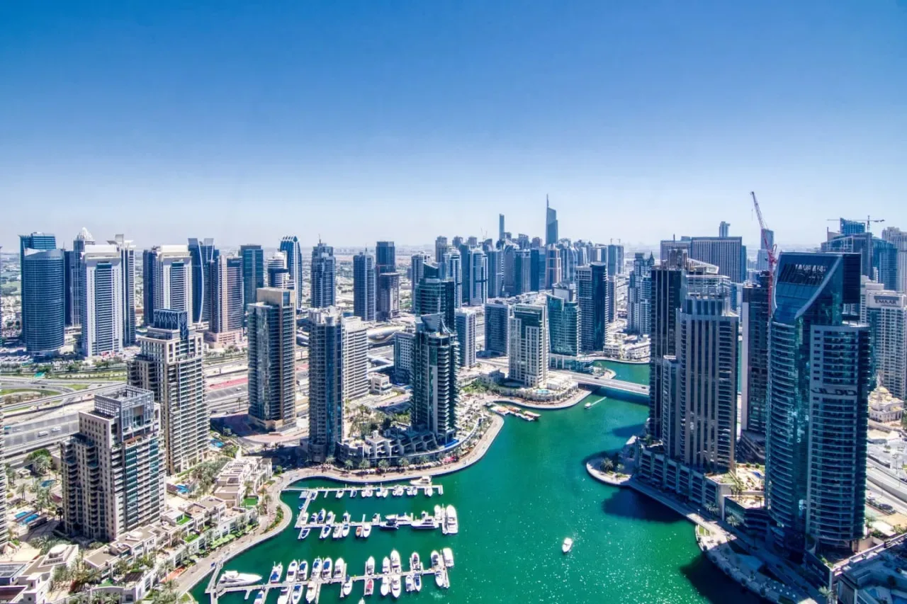Un horizonte urbano se alza junto a una costa turquesa con marinas.