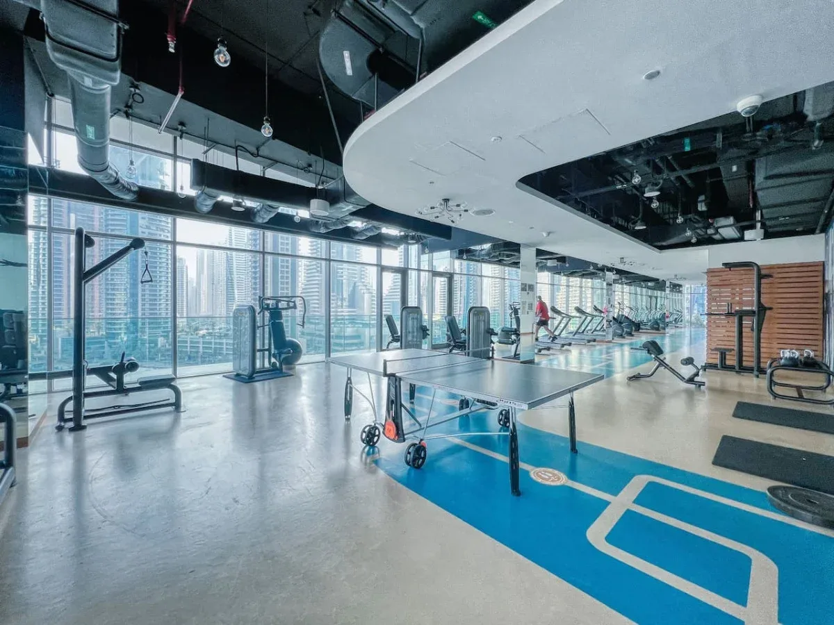 Un gimnasio con máquinas de ejercicio y una zona de entrenamiento azul marcada.