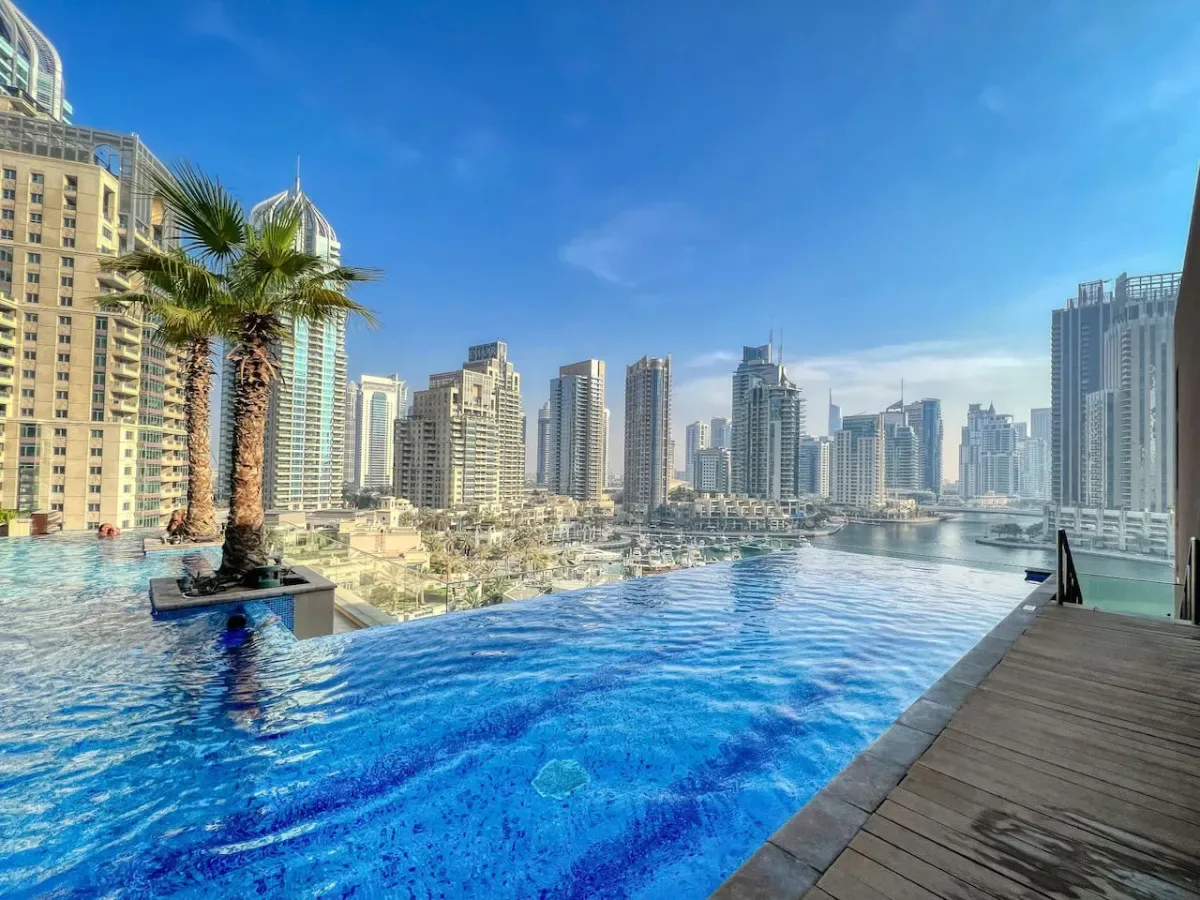 Una piscina en la azotea ofrece vistas del horizonte urbano, con palmeras en el borde.