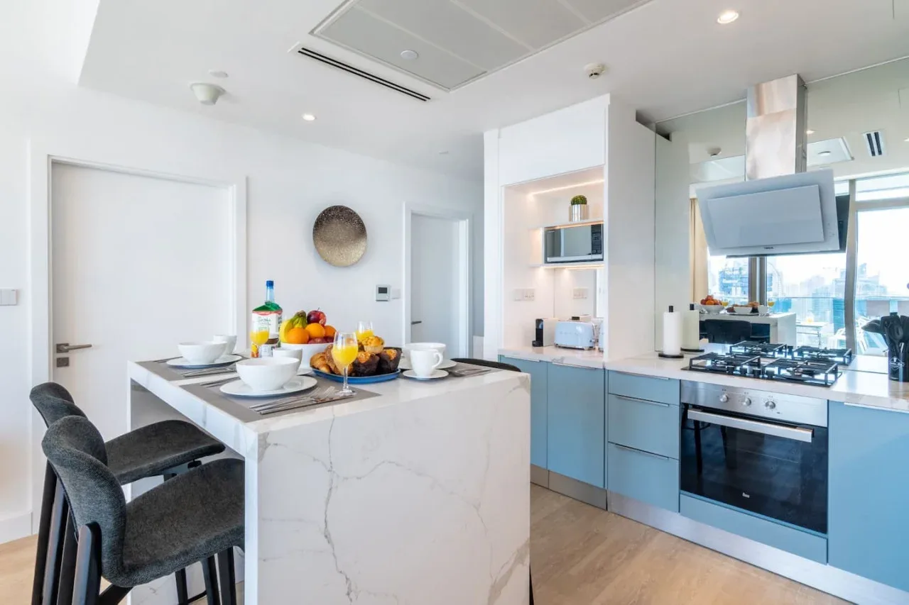 Una cocina moderna y luminosa con una isla central y gabinetes azules.