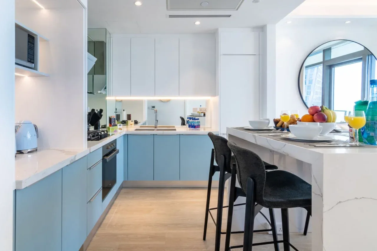 Una cocina moderna y luminosa con gabinetes azul claro y una barra con asientos.