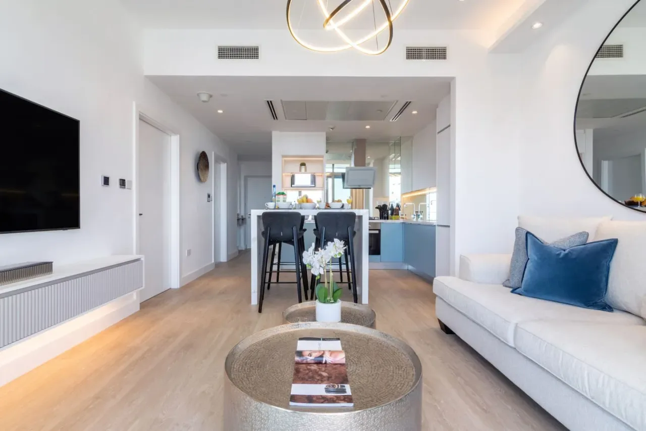 Una sala de estar moderna se abre a un comedor y una cocina, con un sofá blanco.