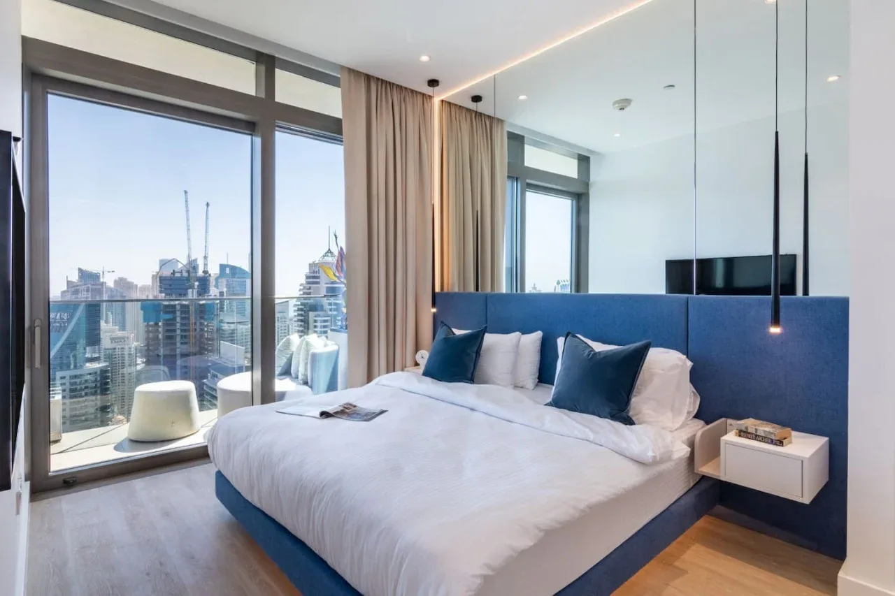 Un dormitorio moderno con una cama junto a ventanales con vistas a la ciudad.
