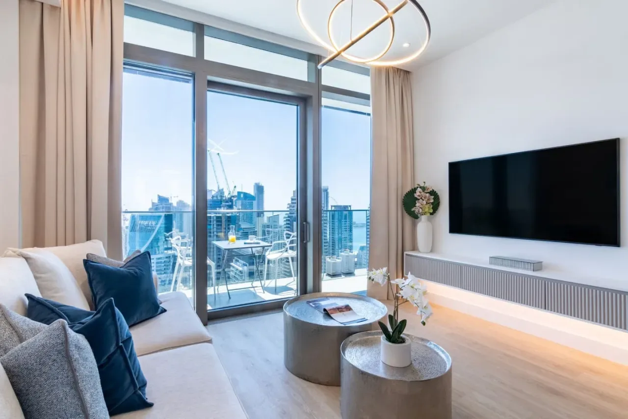 Una sala luminosa con ventanas de piso a techo y una zona de estar.
