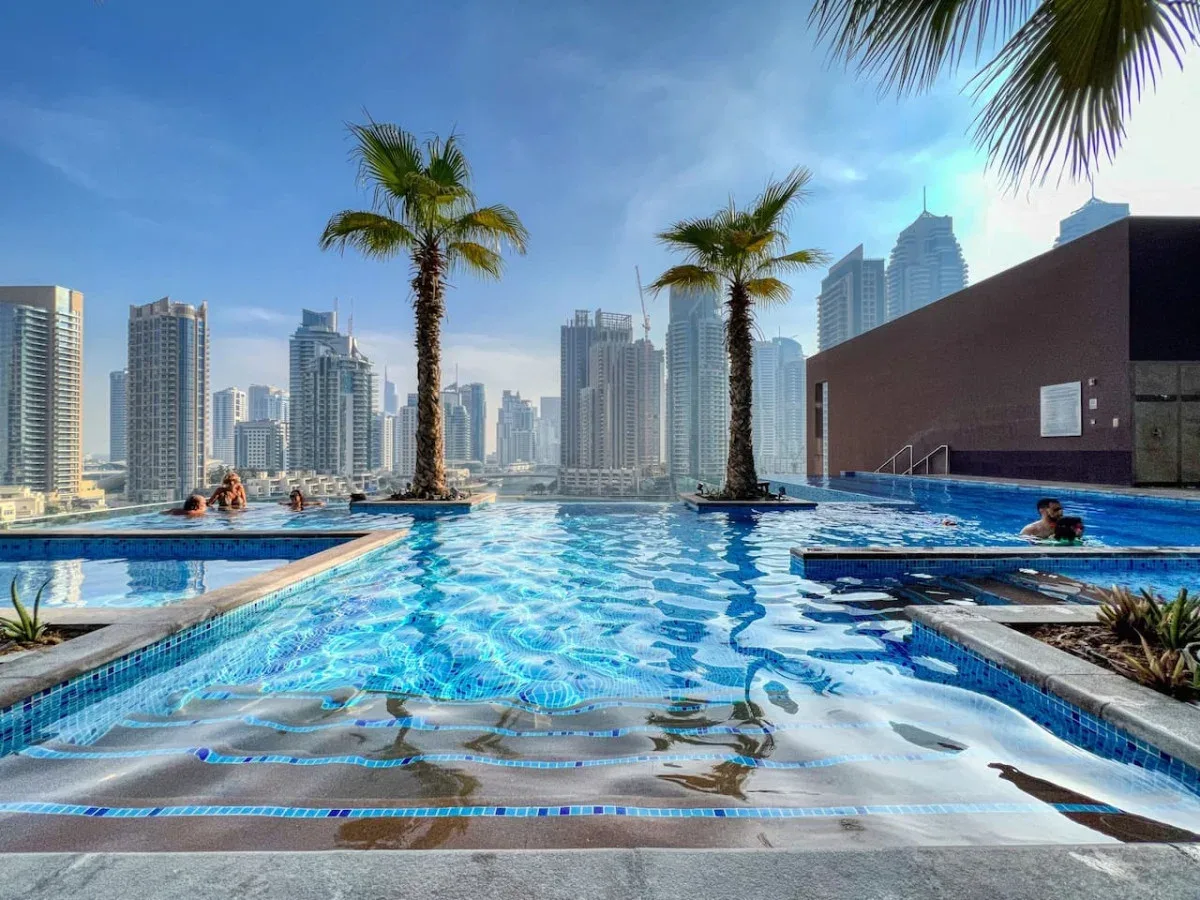 Una piscina en la azotea ofrece vistas del horizonte urbano, con palmeras junto al agua.
