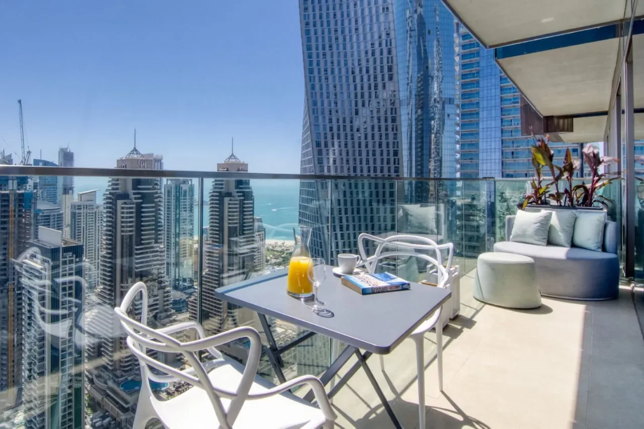 Una zona de estar en un balcón con mesa ofrece vistas al perfil urbano y al mar.