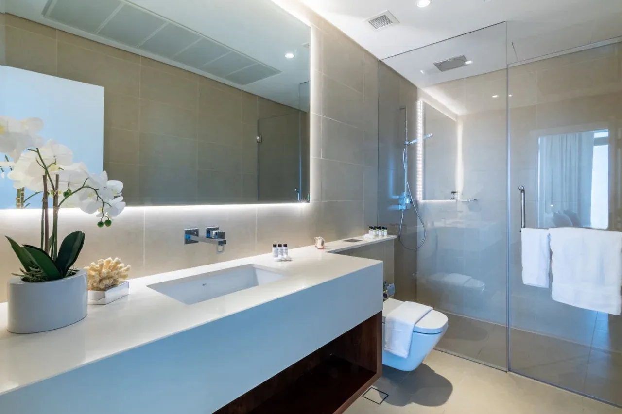 Un baño moderno con un tocador largo, lavabo y ducha de vidrio.