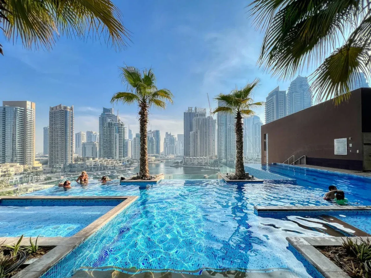 Una piscina en la azotea contempla el horizonte de la ciudad, con palmeras junto al agua.