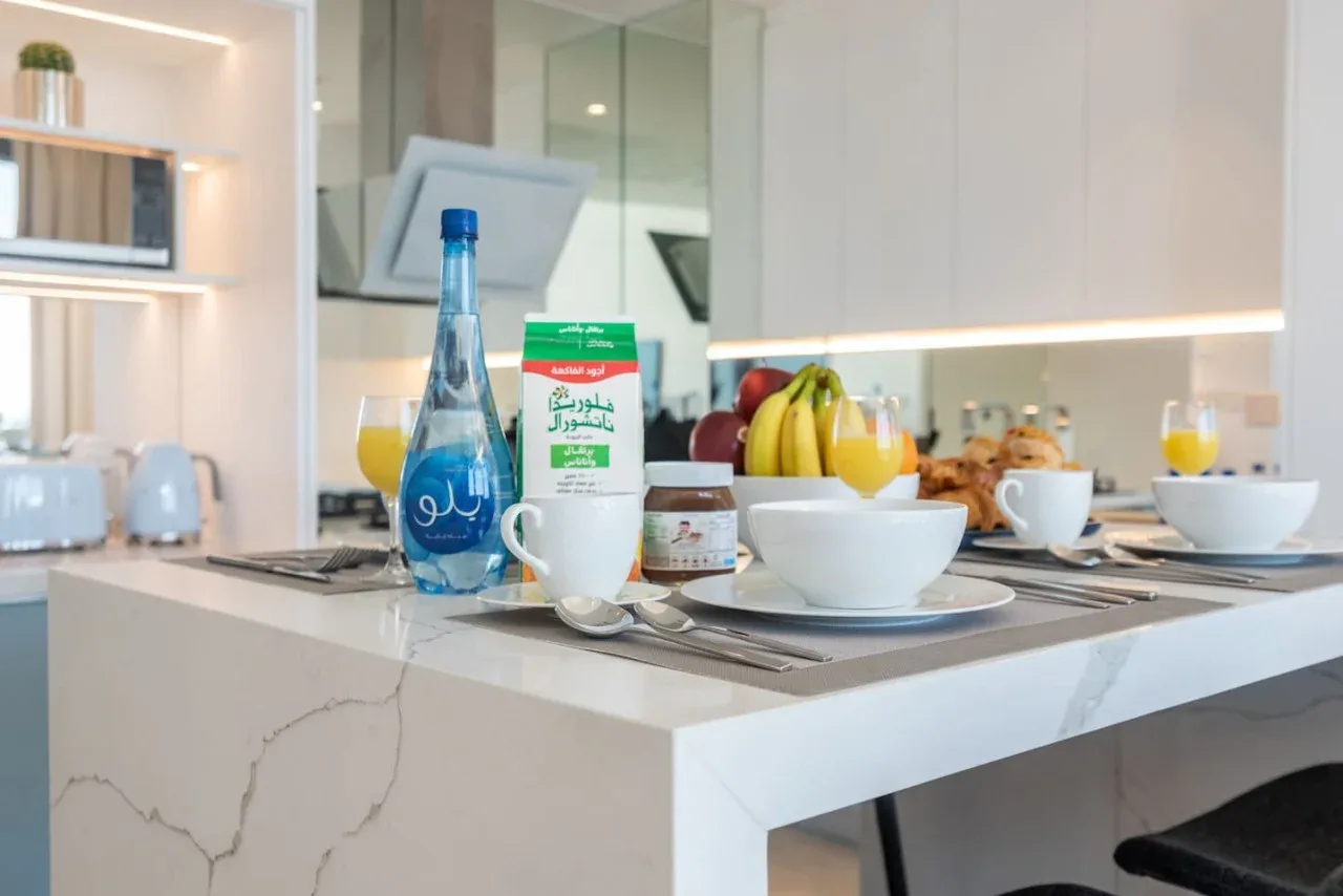 Una encimera de cocina luminosa muestra platos de desayuno y un cuenco de fruta.
