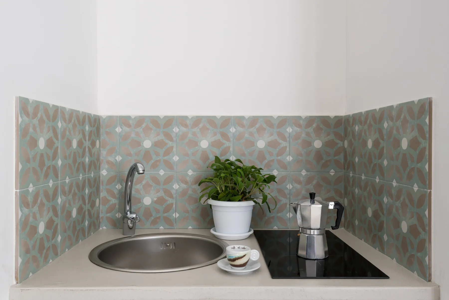 Una encimera de cocina compacta con una cafetera de estufa y una planta en maceta.