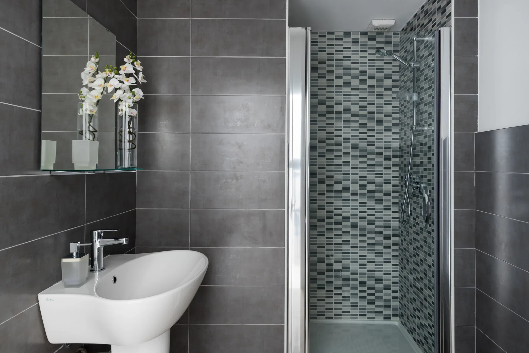 Un baño moderno con una bañera independiente y una ducha revestida de azulejos.