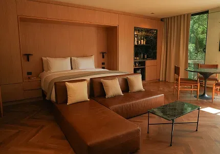Master Suite bedroom with a bed, leather sofa, small table and bar.