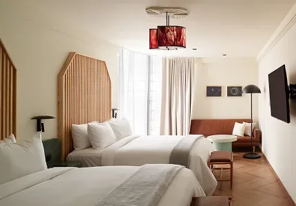 Double Suite room with two beds, sofa, television and a distinctive lamp.