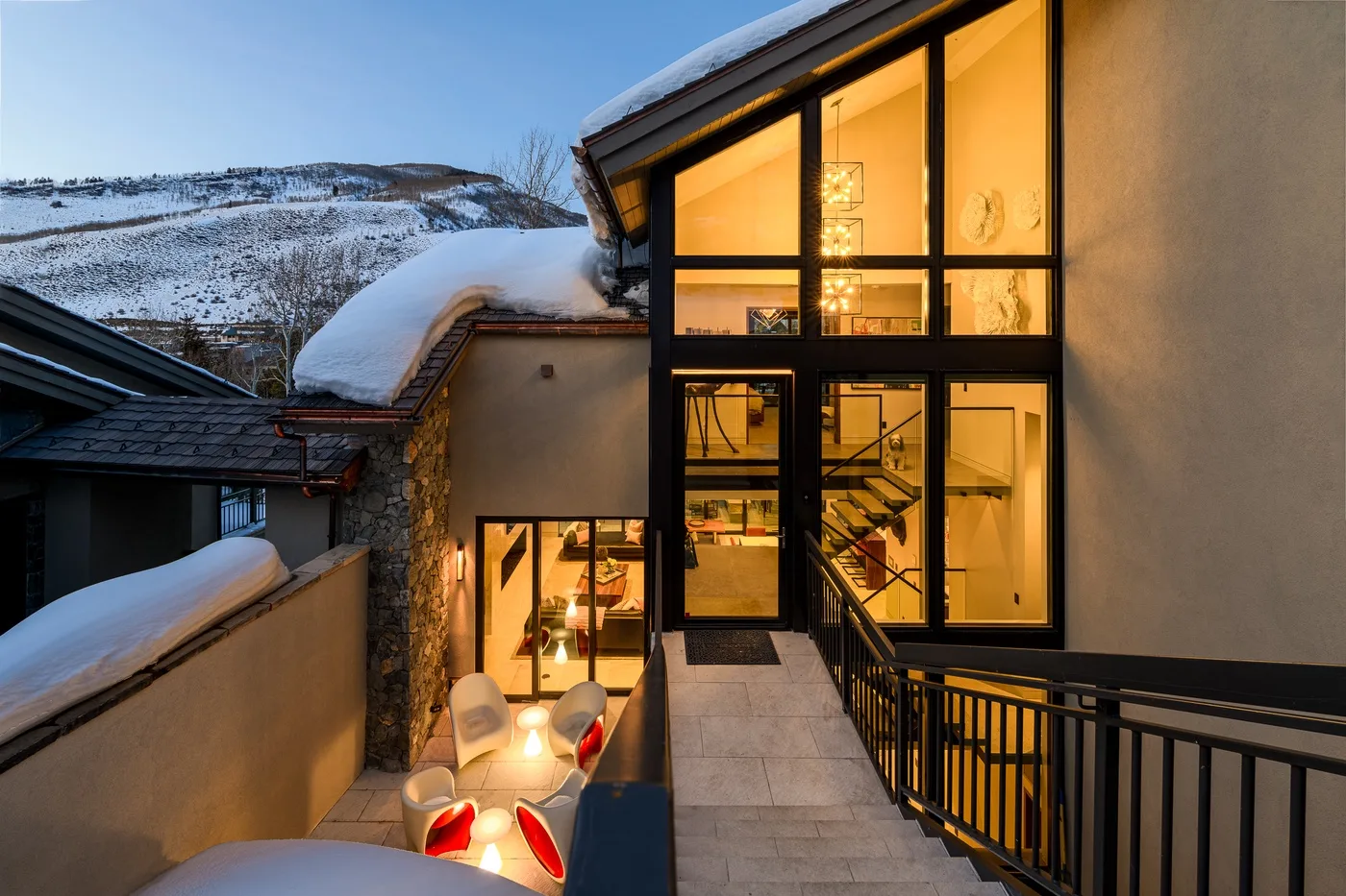 A snow-covered building with warm light glowing through large windows.