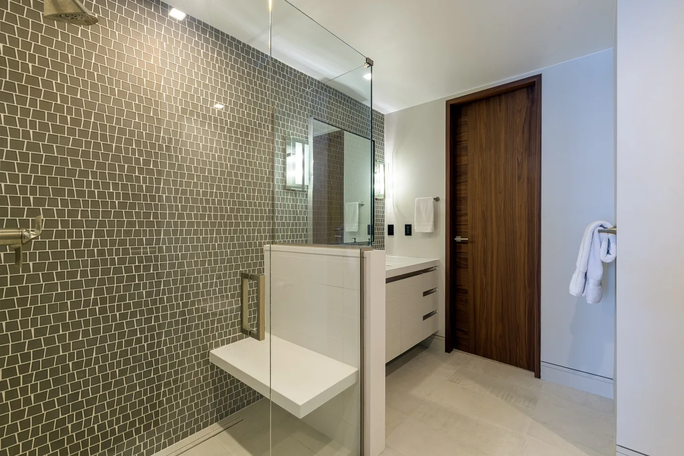 A modern bathroom with a glass shower, tiled wall, and vanity.