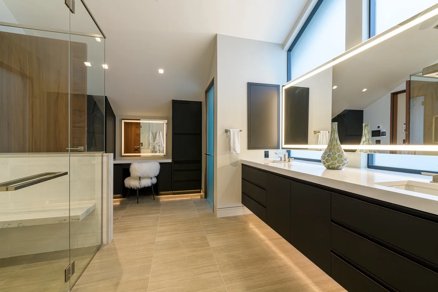 A spacious bathroom with a glass shower, a long vanity, and large mirrors.