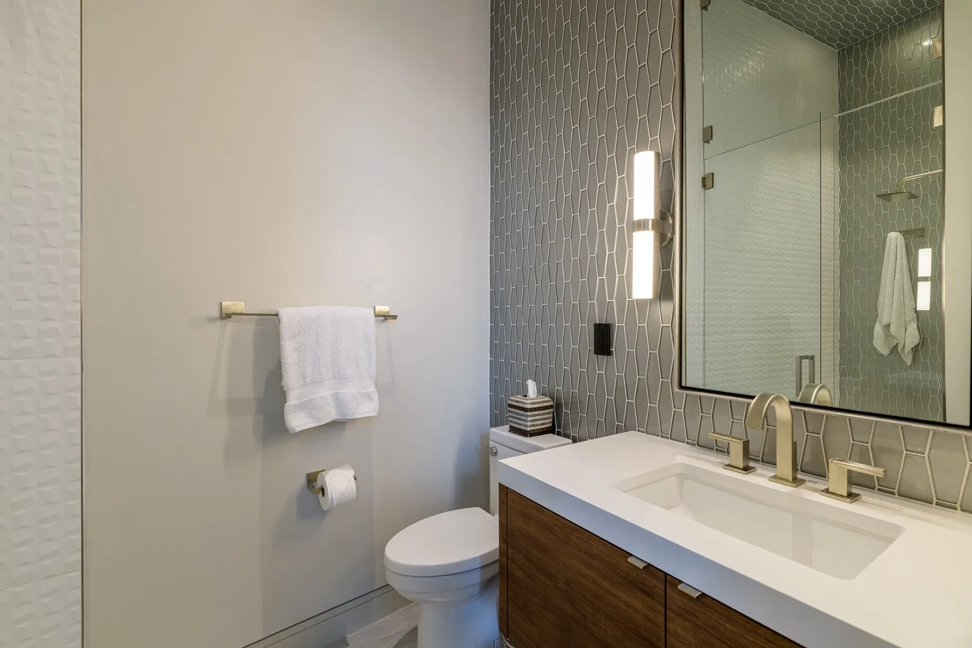 A bathroom with a toilet, towel, and vanity beside a large mirror.