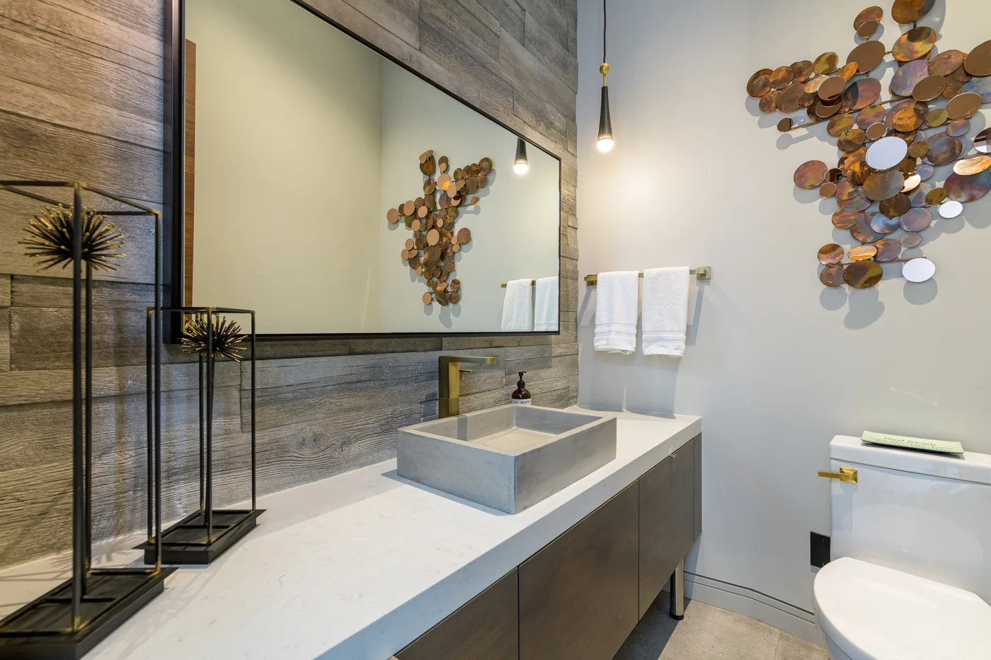 A modern bathroom with a wide vanity, wall mirror, and decorative wall art.