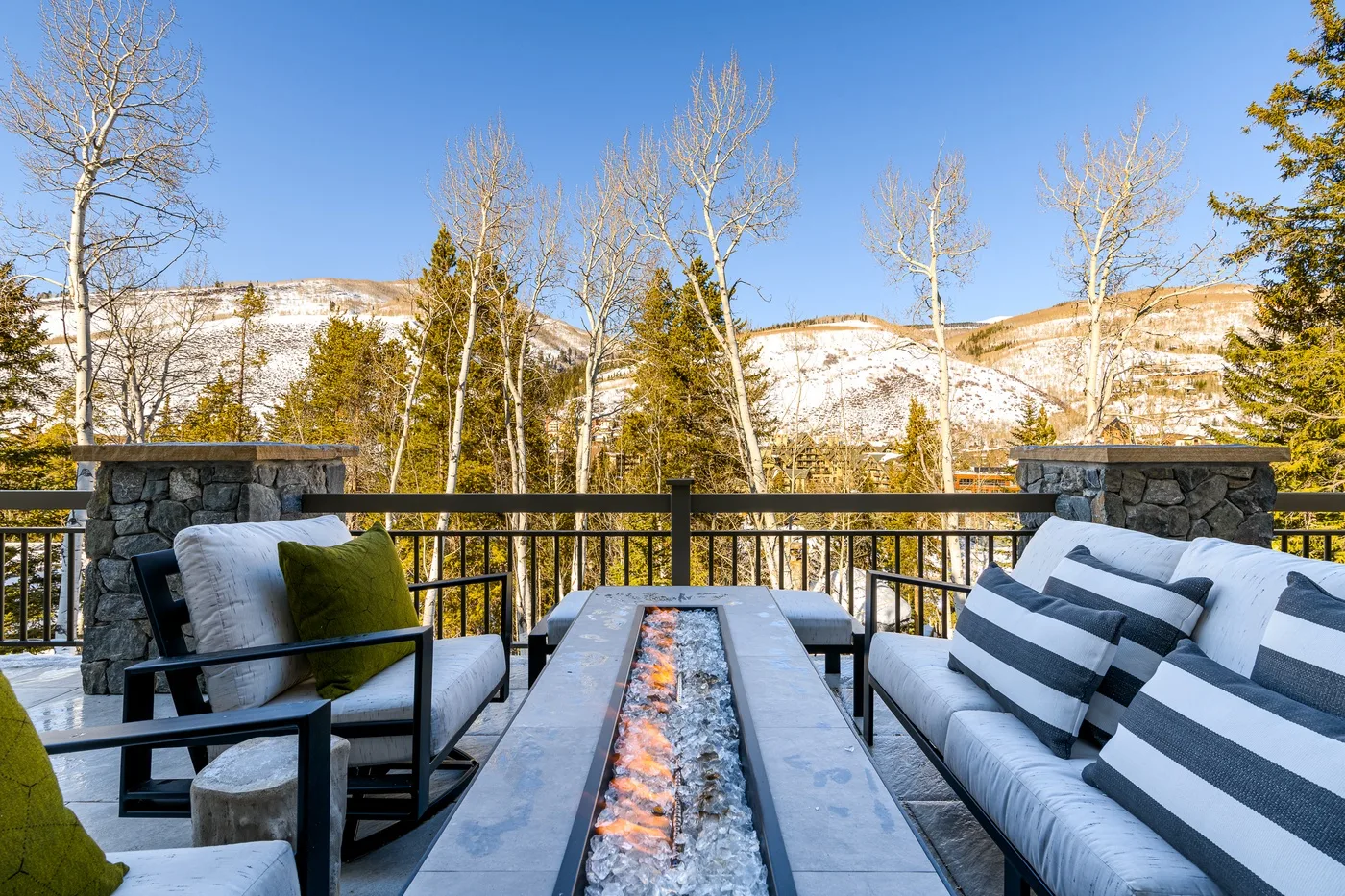 An outdoor seating area overlooks snow-covered hills, with a long fire feature between the seats.