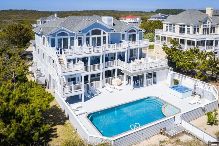 Una casa de estilo costero tiene balcones escalonados y una piscina exterior.