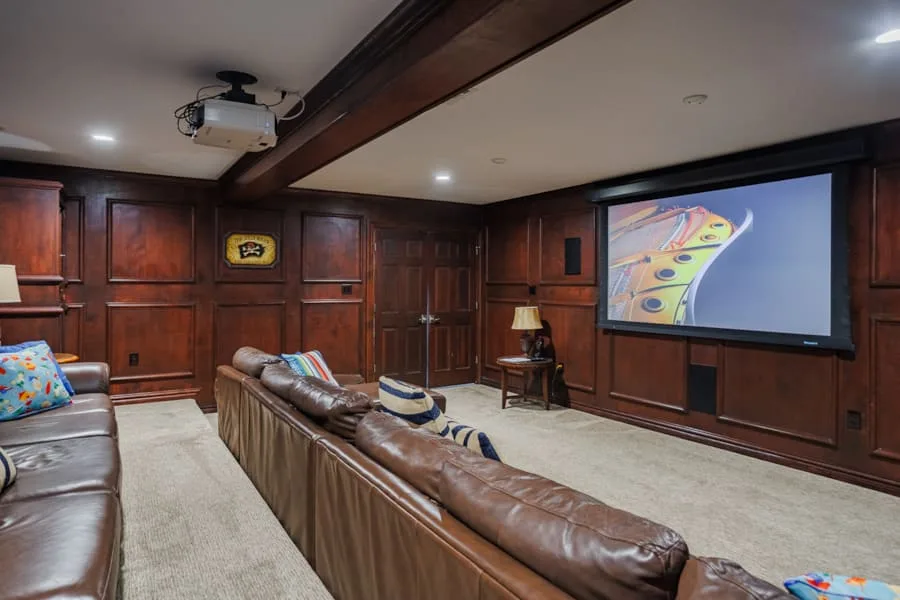 Una sala de cine en casa con asientos de cuero y una gran pantalla de proyección.