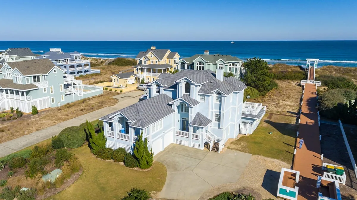 Aerial view of coastal homes beside a boardwalk and the ocean.