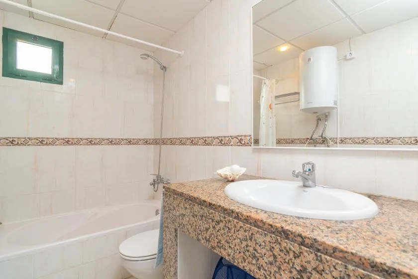 Un baño con bañera, inodoro y lavabo bajo un espejo grande.
