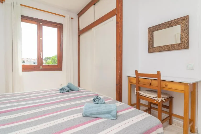 Un dormitorio con una cama a rayas, una ventana y un escritorio de madera.