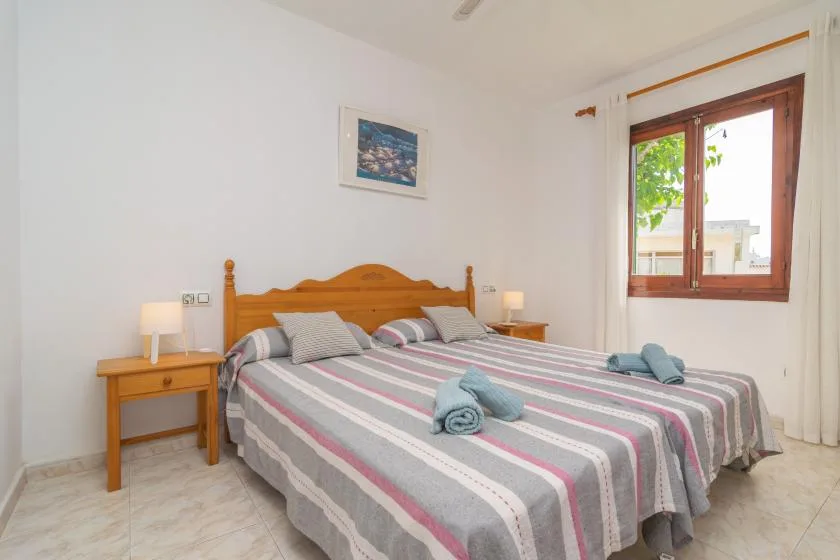 Un dormitorio con una cama de madera, ropa de cama a rayas y una ventana.