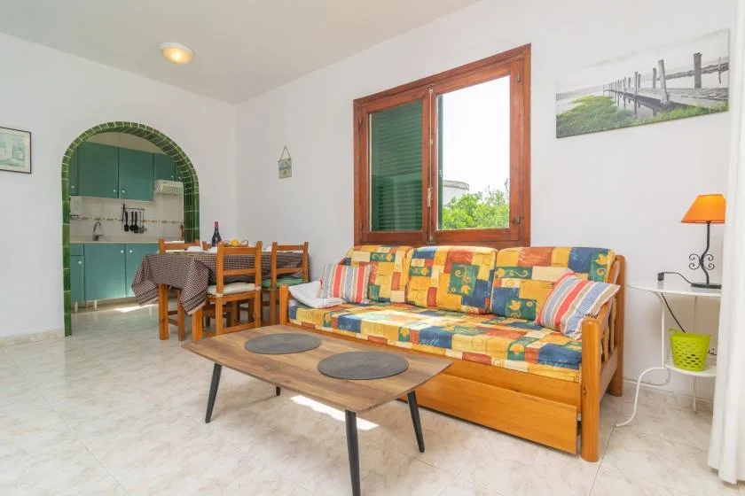 Una sala luminosa con asientos coloridos junto a un comedor abierto.