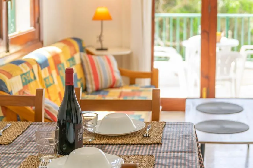 Una mesa de comedor está frente a una zona de estar colorida junto a puertas de vidrio.