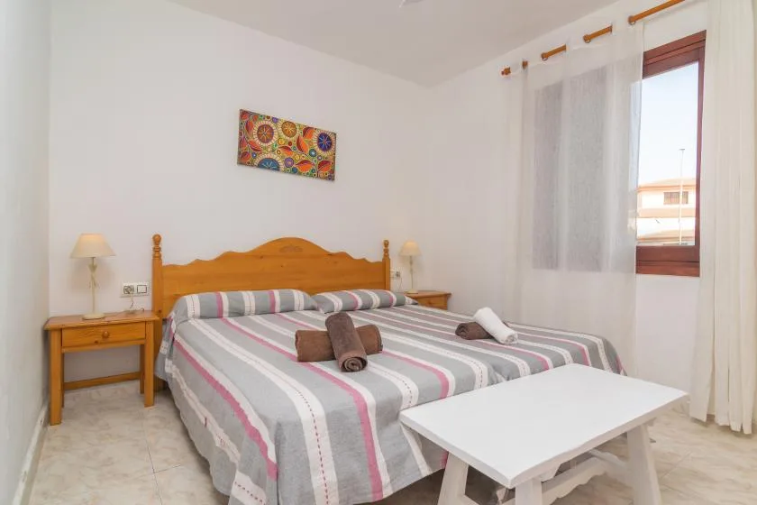 Un dormitorio con una cama doble, ropa de cama a rayas y una mesa blanca.