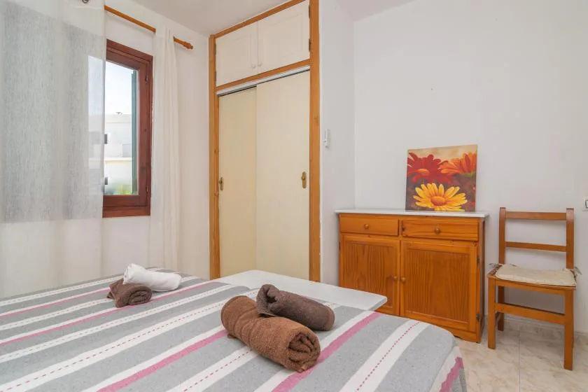 Un dormitorio con una colcha a rayas, un mueble de madera y una silla.