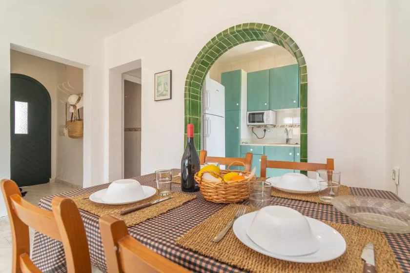 Una mesa puesta con platos está frente a un arco que da a la cocina.