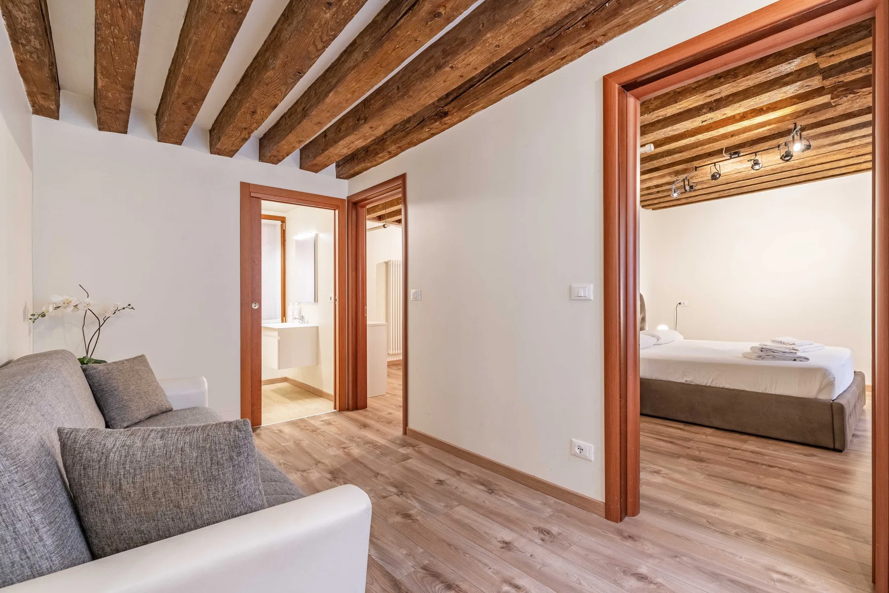 Un dormitorio y una zona de estar contigua con vigas de madera a la vista.