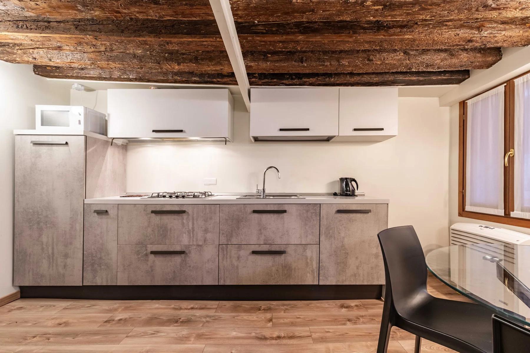Una cocina compacta con gabinetes grises, una estufa y una mesa de comedor.